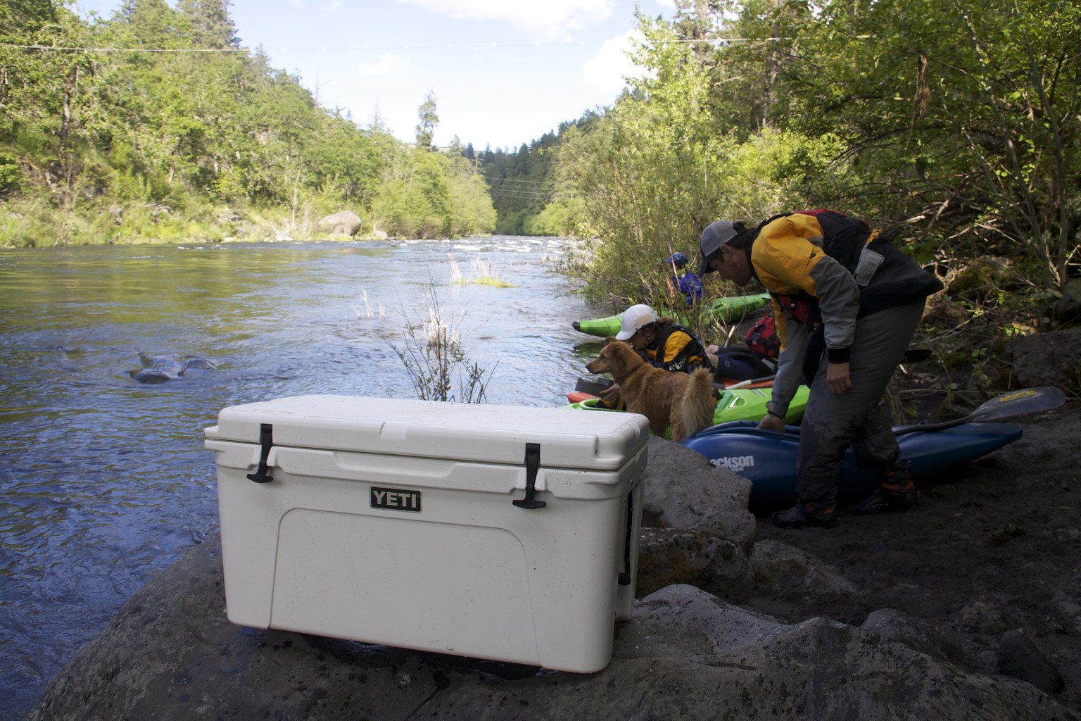 A Yeti cooler on the bank of a river, which is one of the best can coolers you can buy.