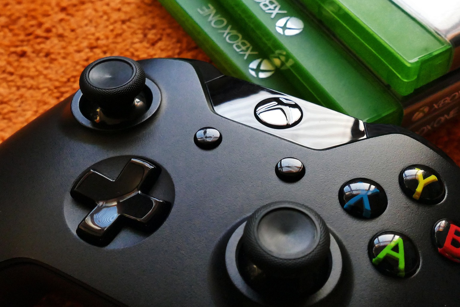 A controller, which is one best xbox one accessories, and a stack of game boxes.